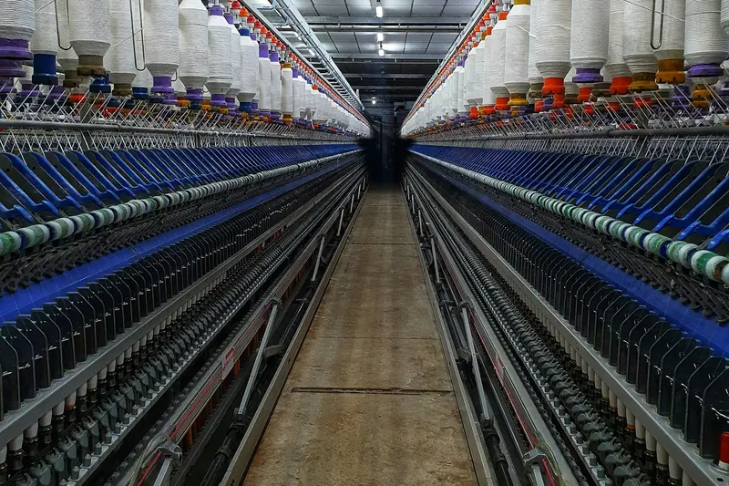 Bir iplik fabrikasında uzun sıralar hâlinde dizilmiş makineler ve renkli iplik bobinleri