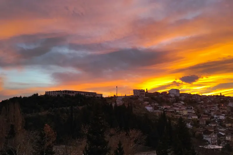 İzmit'te gün batımında turuncu bulutların altında, ağaçlıklı bir tepe üzerindeki yerleşim