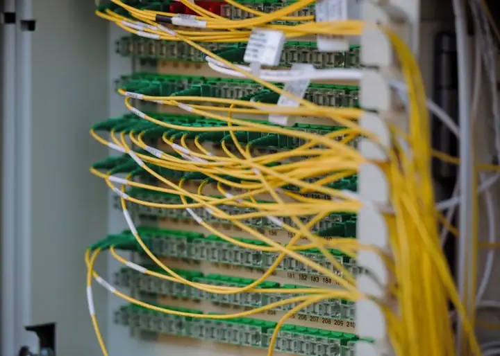 Yellow fiber optic patch cables plugged into a green connector panel – VPS, VDS and cloud hosting